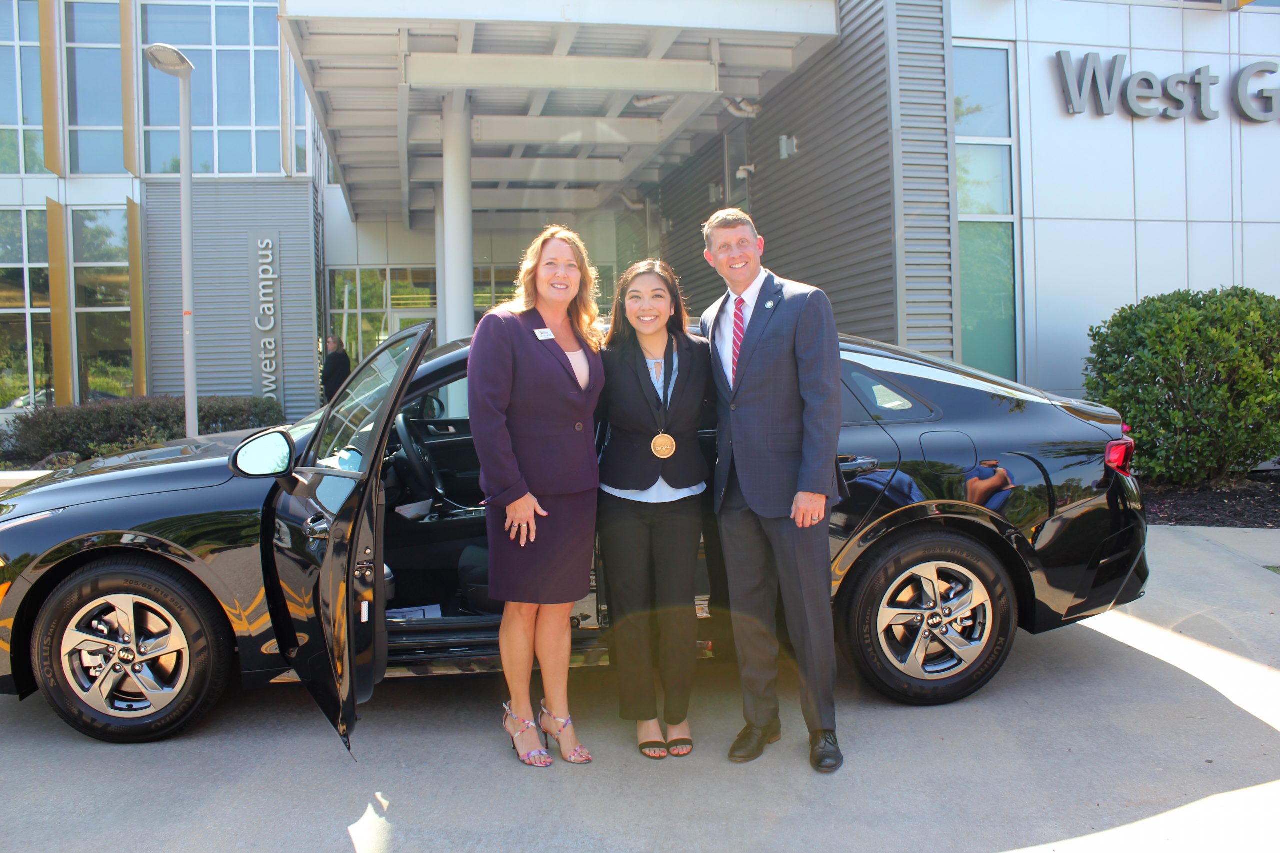 Rodriguez with president and commissioner in front of a kia