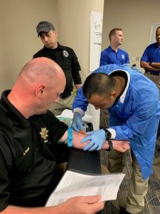 Police officers practicing phlebotomy