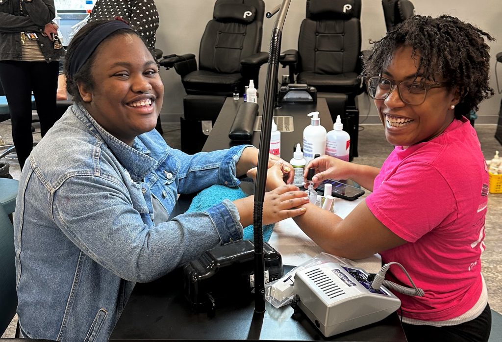 Cosmetology student giving manicure to client