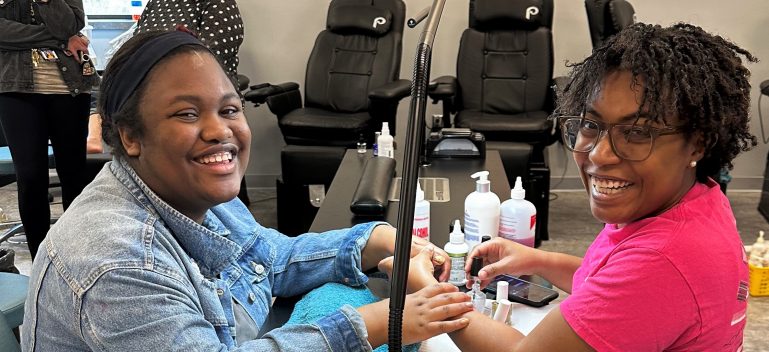 Cosmetology student giving manicure to client