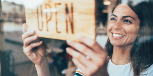 woman adjusting an open sign in a window
