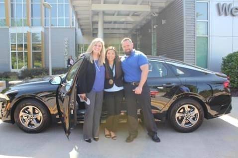 elizabeth and instructors with car by campus